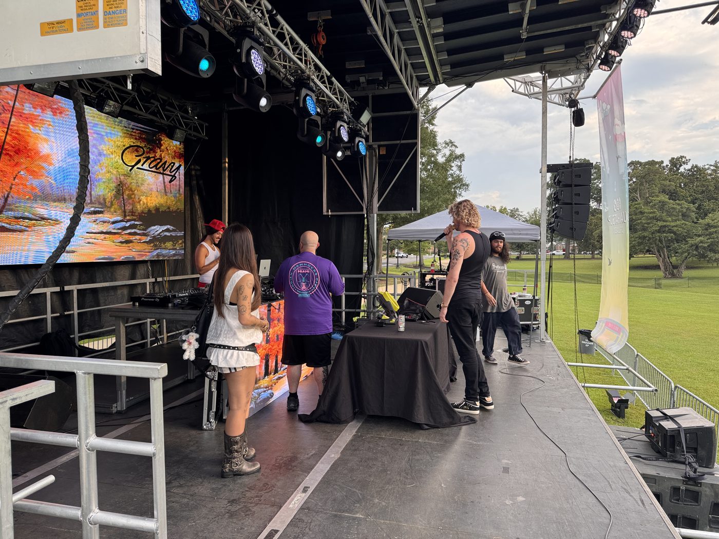 Outdoor festival DJ table with crowd and stage lighting